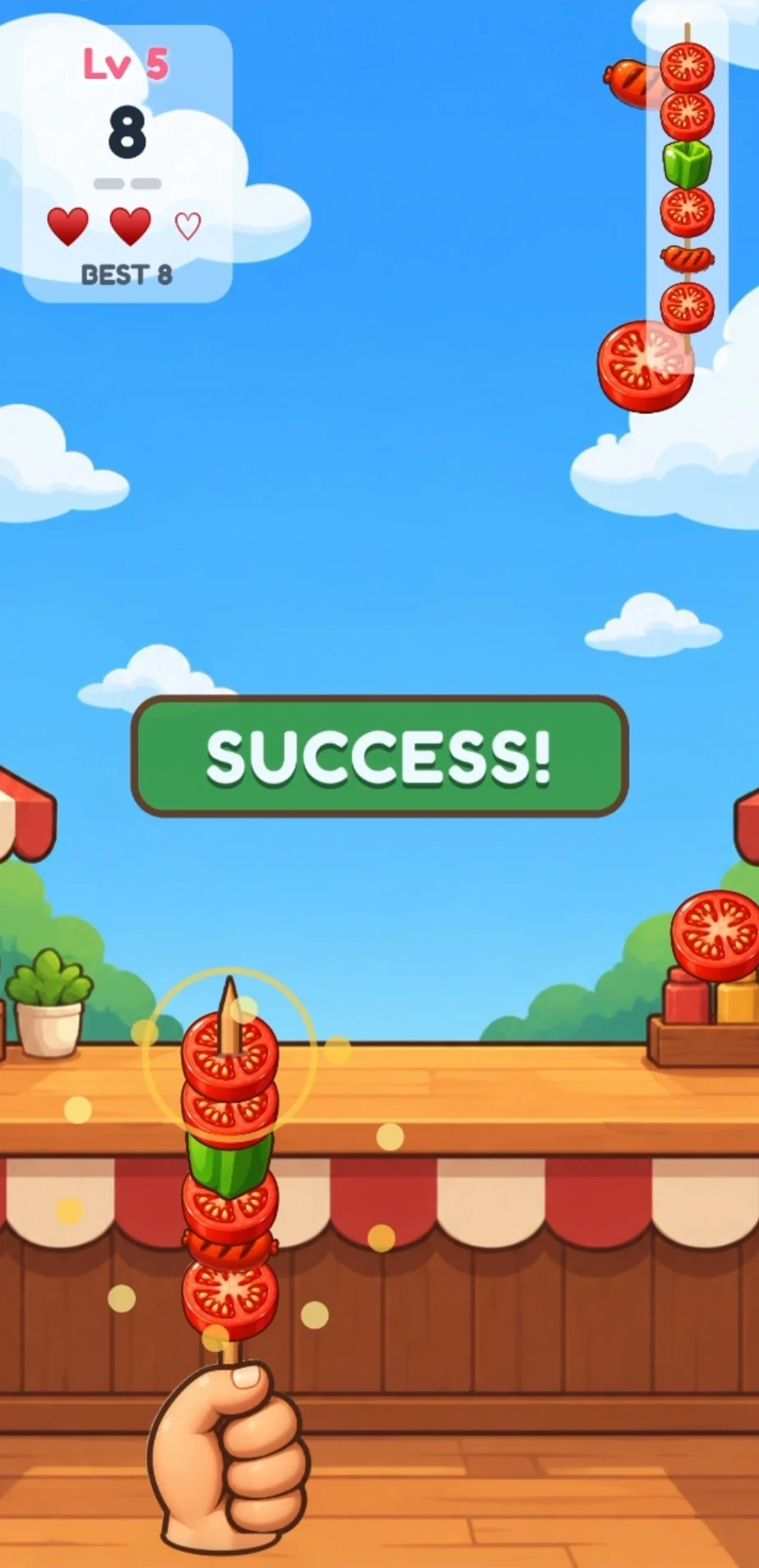 Skewer Snap gameplay at level 5: a hand holds a skewer stacked with tomatoes, a green pepper and a sausage, the target skewer is in the top-right corner, two of three hearts are left, and a SUCCESS! banner is showing.